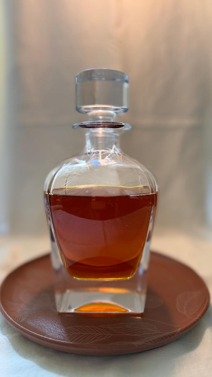 Decanter de vidro com tintura âmbar sobre prato de barro