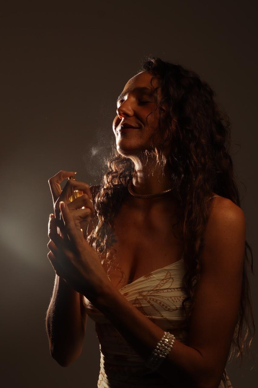 Mulher borrifando perfume natural, luz dourada